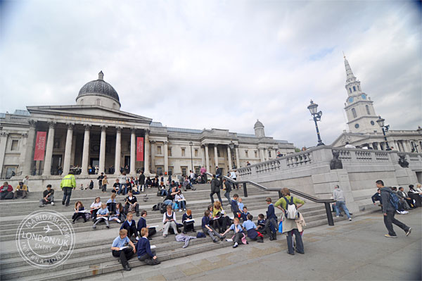 National Gallery, Trafalgar Square, London, showing crowd of people sitting at steps