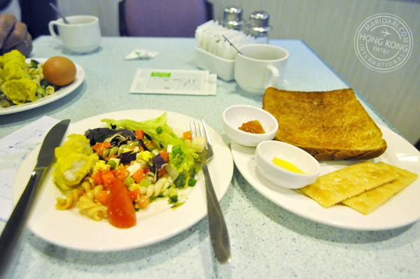 Evergreen Hotel Hong Kong buffet breakfast spread - spiral pasta with sweet tomato sauce, wonton, hard-boiled eggs, fresh salad with dressing, bread, crackers, jam and butter, coffee